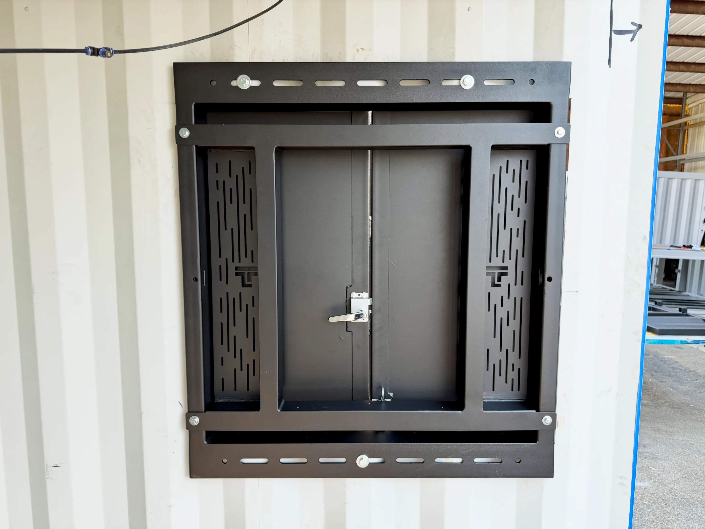 Taylor'd bolt-on Training Window, closed and latched, mounted flush on a container wall